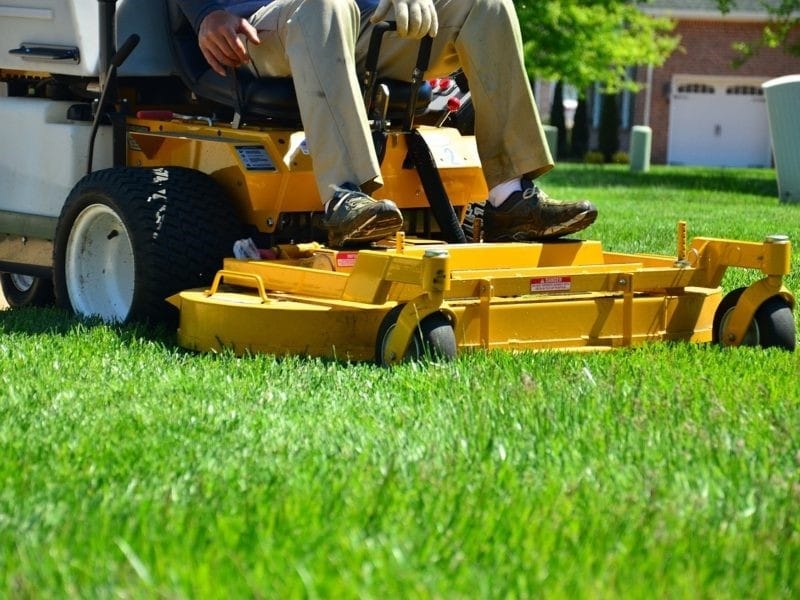 Man in overall and safety helmet trims overgrown grass by grass cutter  Stock Photo - Alamy